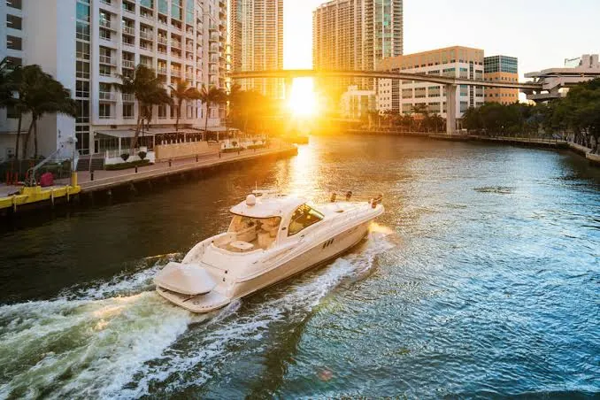 Small boat moving along a city waterway at sunset